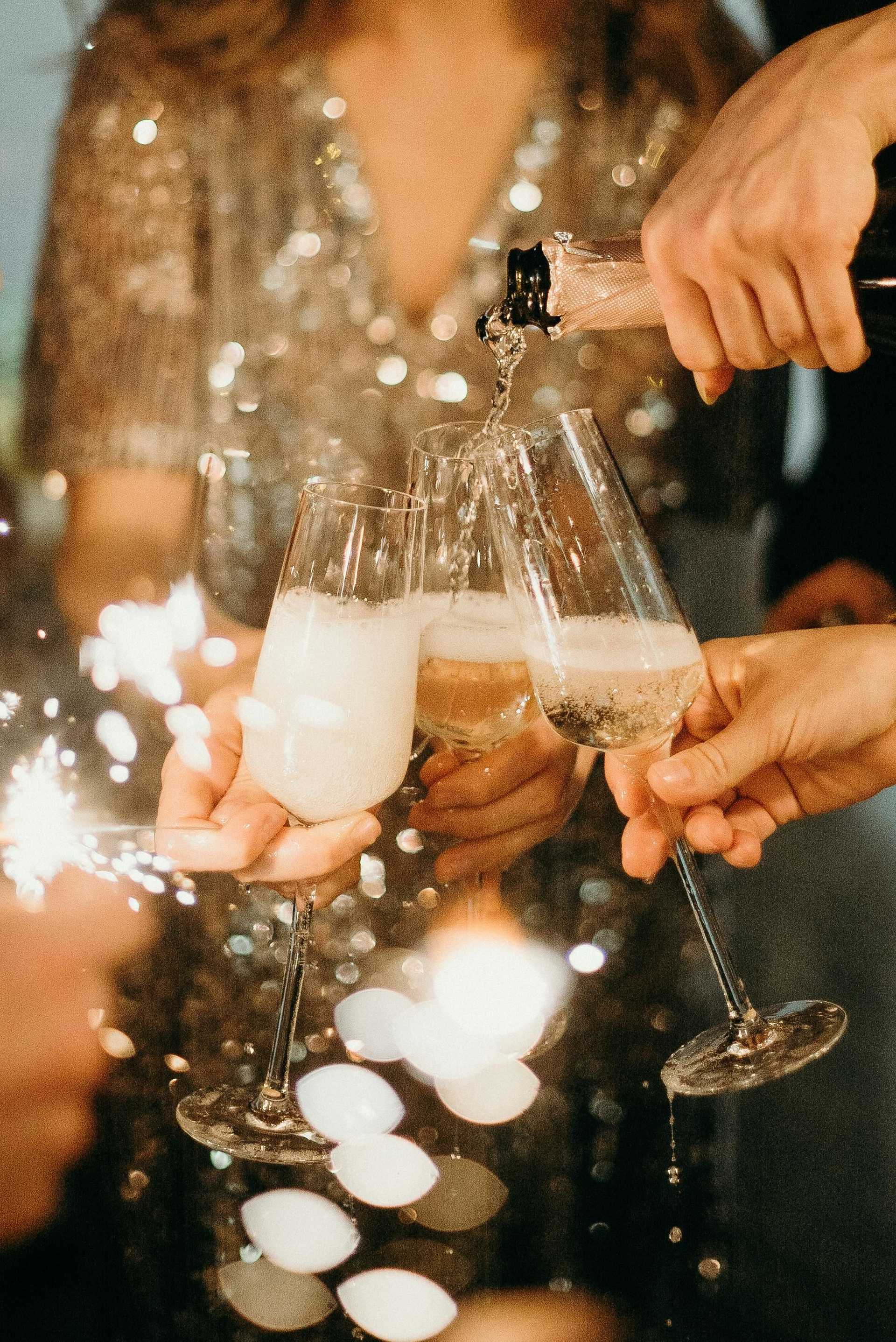 Group toasting with champagne glasses at a festive celebration, sparkling lights in the background.